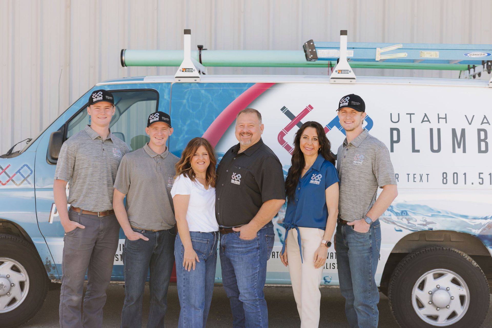 Image of the entire Utah County, Utah UVP Utah Valley Plumbing Team around the plumbing truck van. Utah Valley Plumbing's motto is the company's slogan, "We Solve Problems," standing up and smiling.