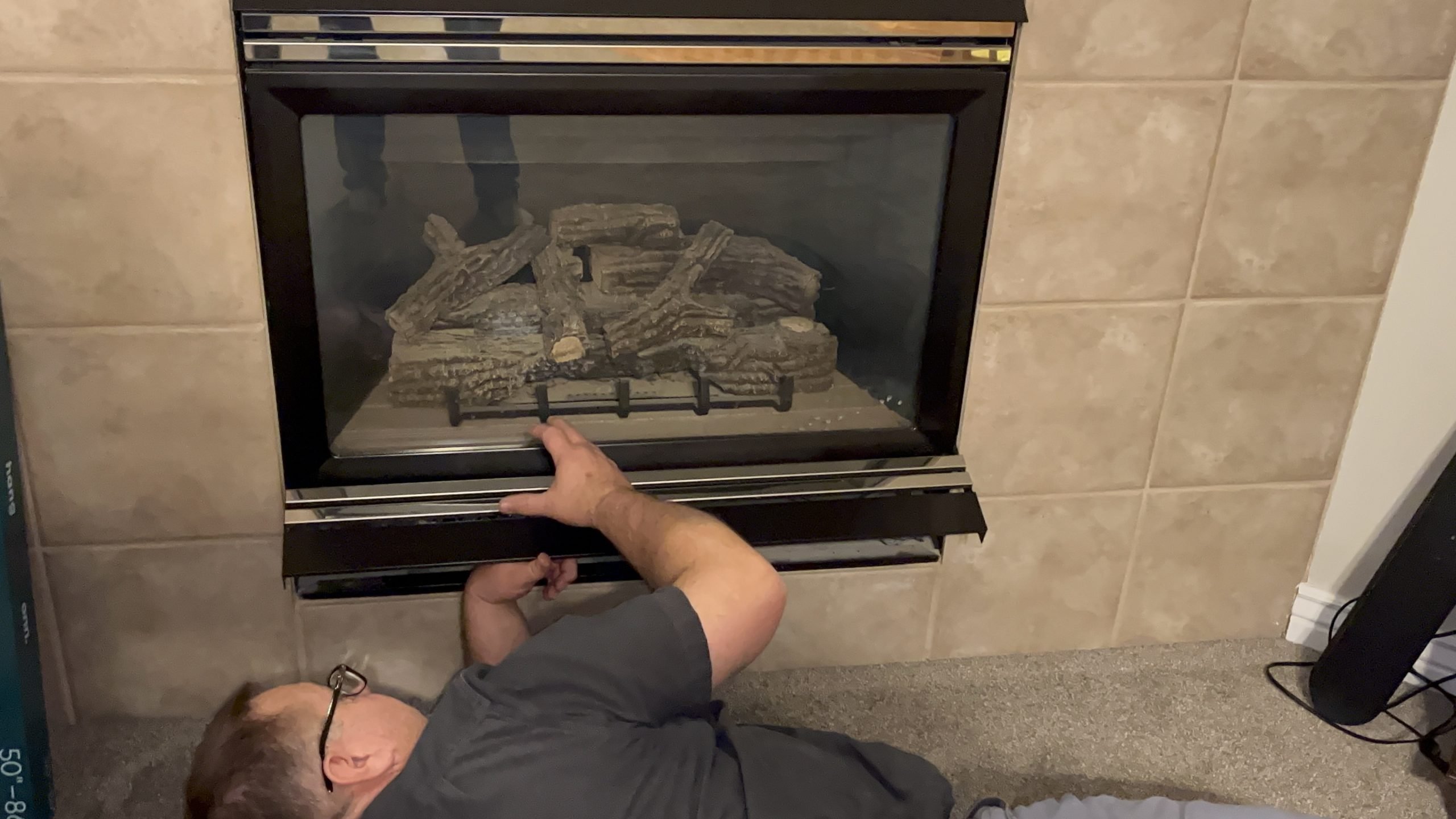 Plumber inspecting and maintaining a gas fireplace insert, showcasing expertise in home heating solutions.